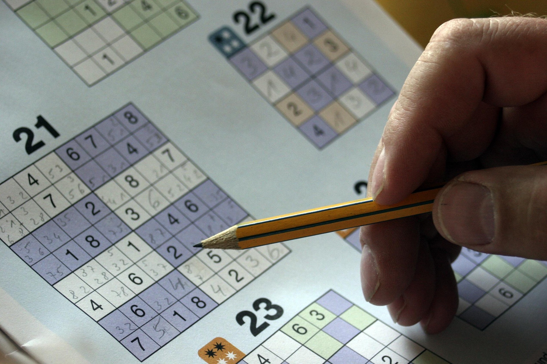 Sudoku-Rätselheft mit Bleistift in der Hand